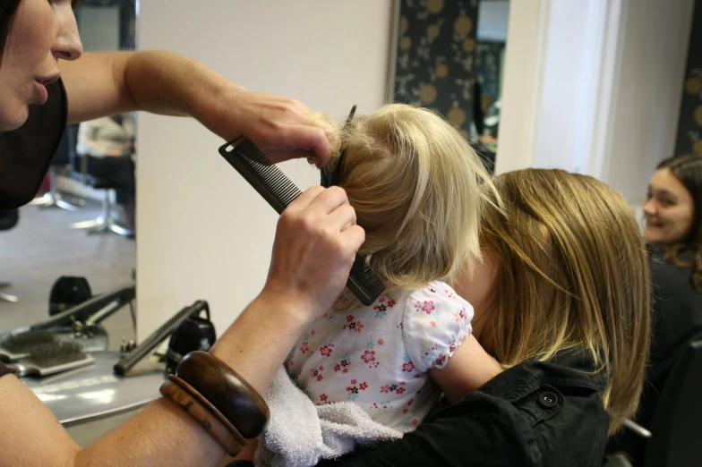 a little girl is being combed by her mom
