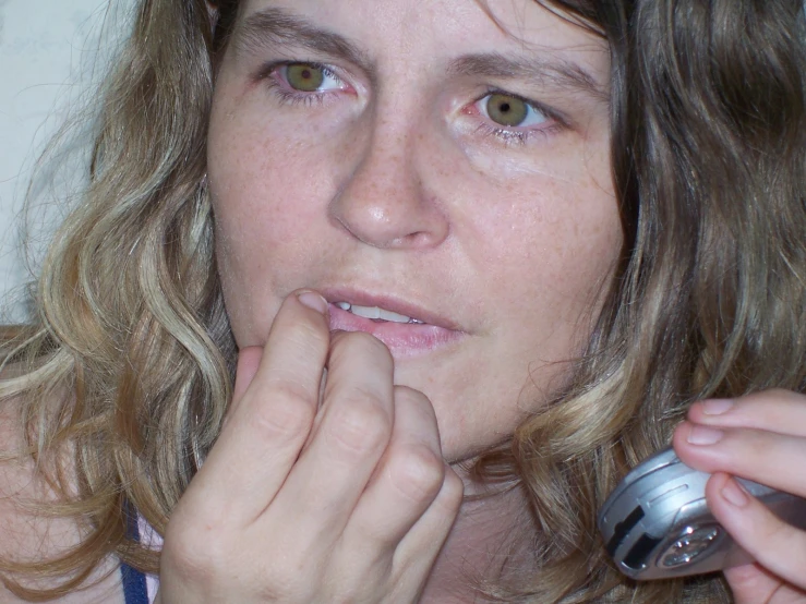 a young woman brushing her teeth and holding an object in one hand