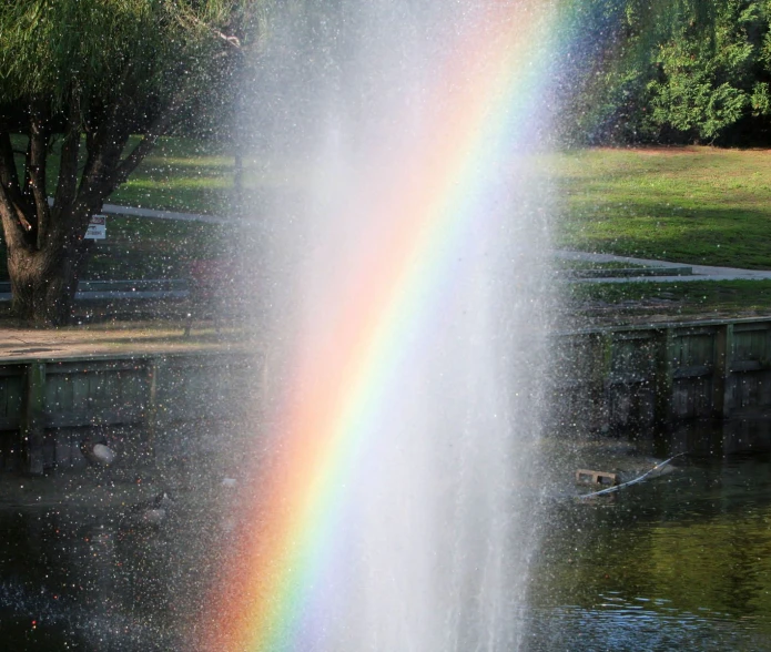 a large rainbow in the sky over water