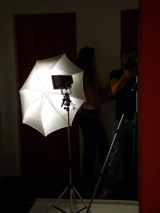 a woman recording a man in front of a white umbrella