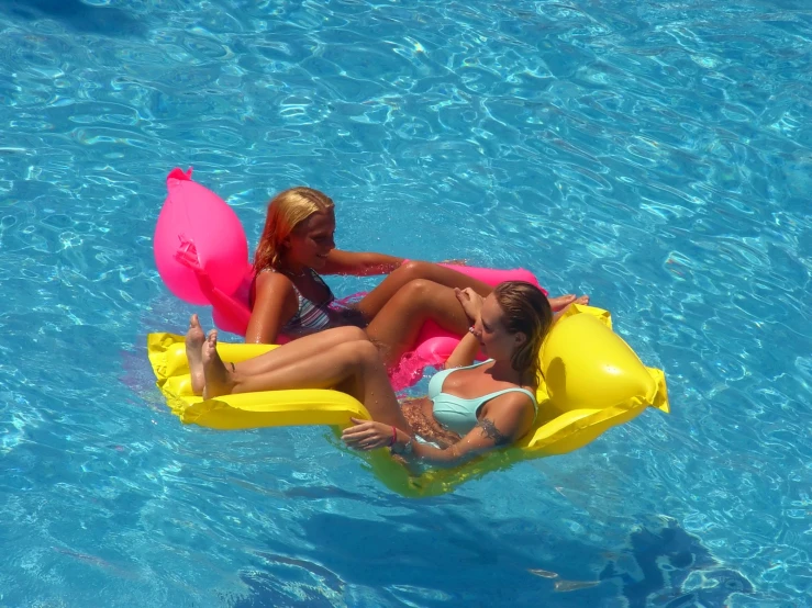 two girls sitting on raft in swimming pool