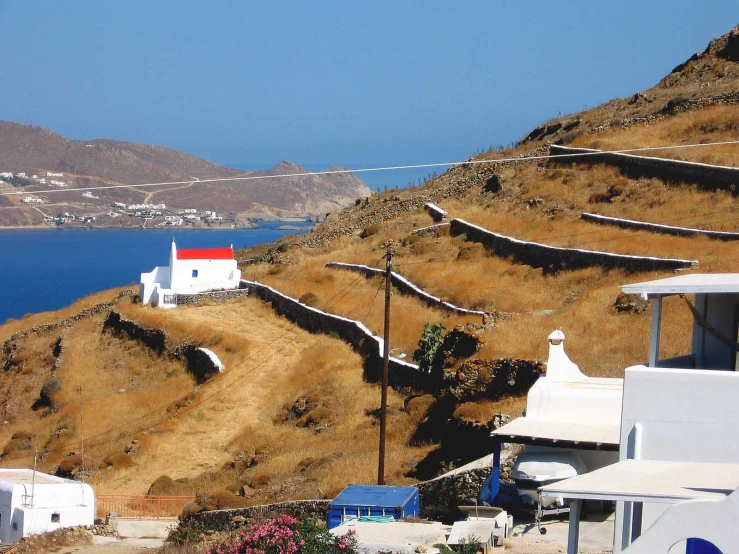 a house is at the top of a small mountain near a lake