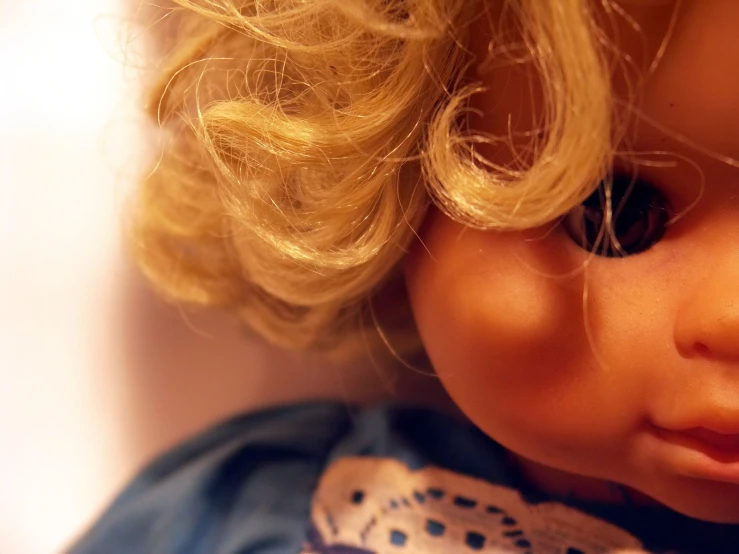 a dolls head with blonde hair wearing a blue dress
