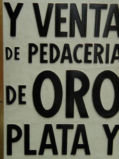 a white sign in spanish and spanish is hanging from the wall