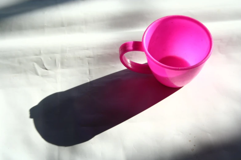 a pink mug sitting on a white blanket on the ground