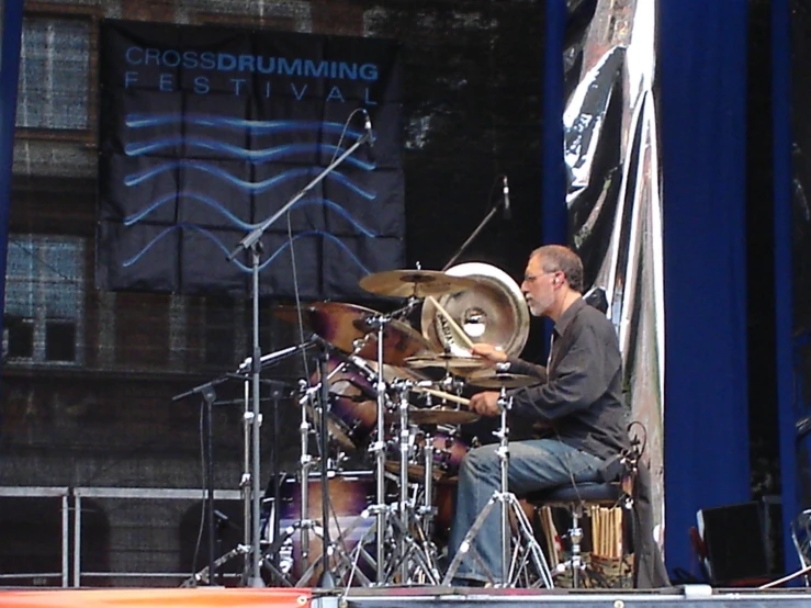 a man sits on top of a drum set