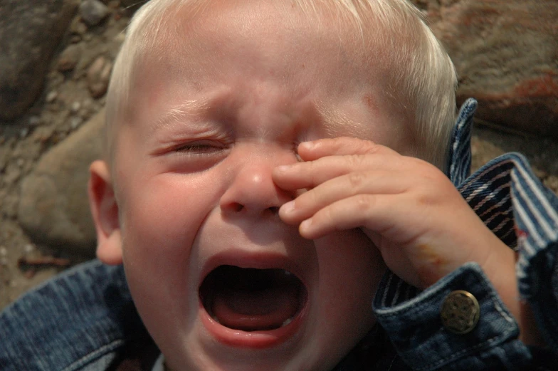 a child holding their hands near their face and covering his eyes