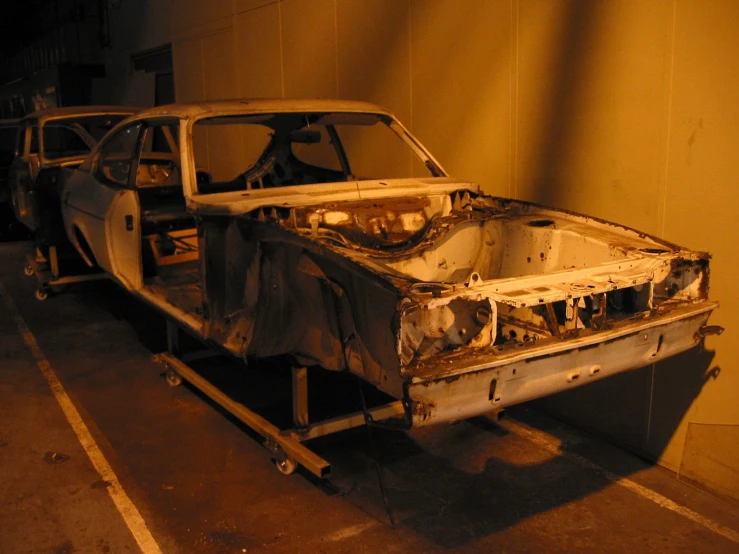 an old abandoned car is shown in a darkened spot