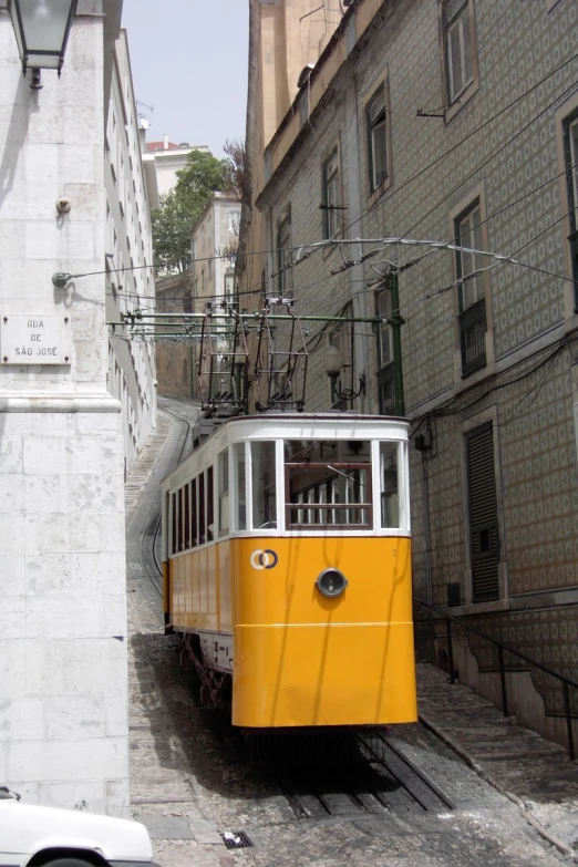 a yellow tram is moving along a city street