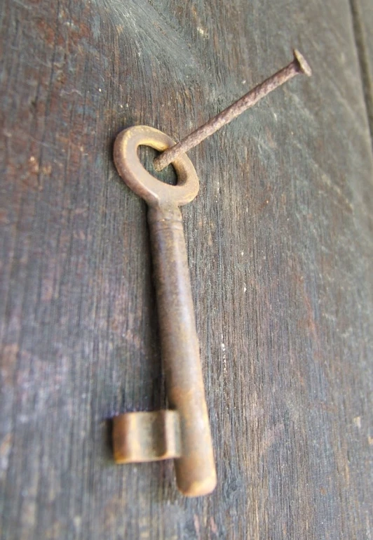 an antique key on a wood surface with nails in it