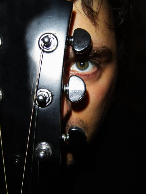 man playing an electric guitar while looking through the strings