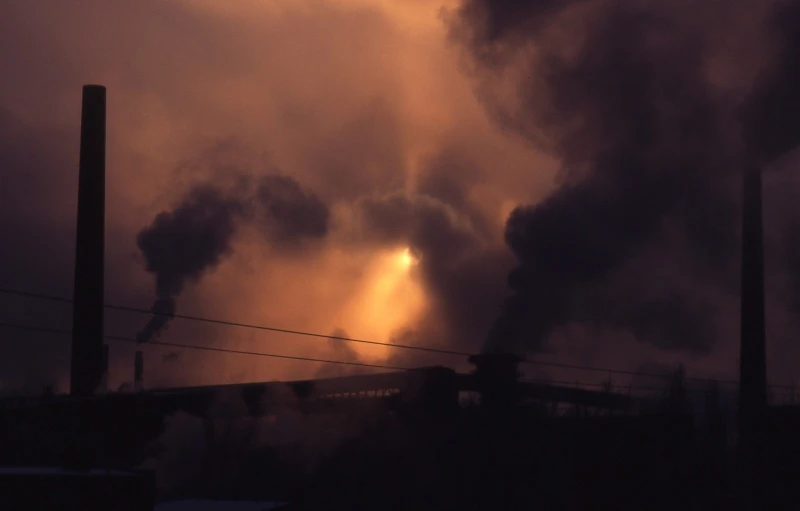 a factory building with smoke pouring out it's chimneys