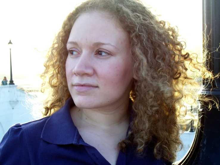 a woman standing next to a mirror with long curly hair