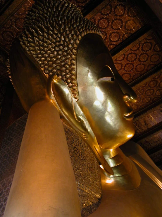 a very big gold vase sitting in front of a large statue