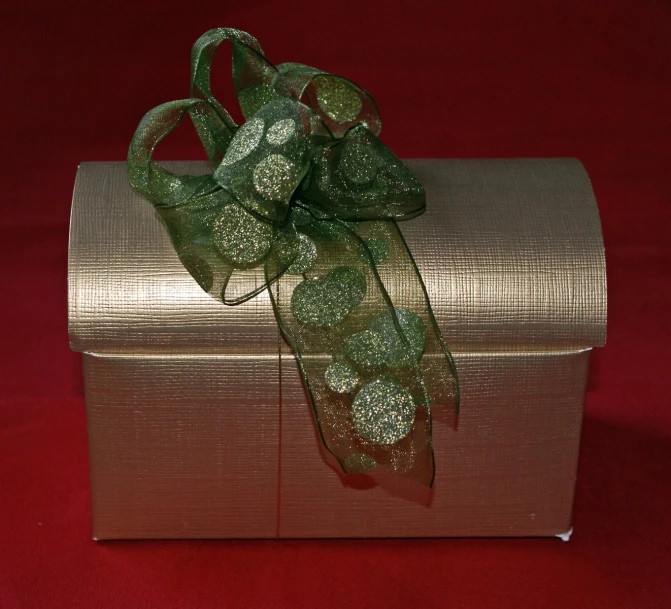 a gold gift box with a green bow on red background