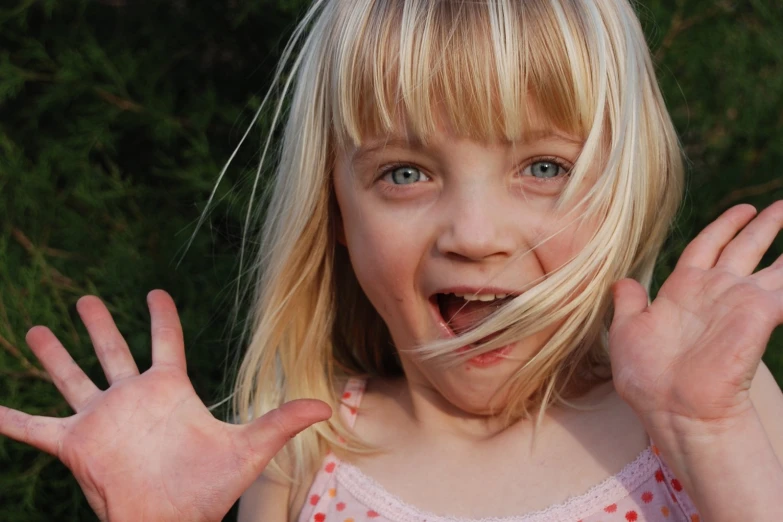 a blond girl with very big hair and hands up in front of her