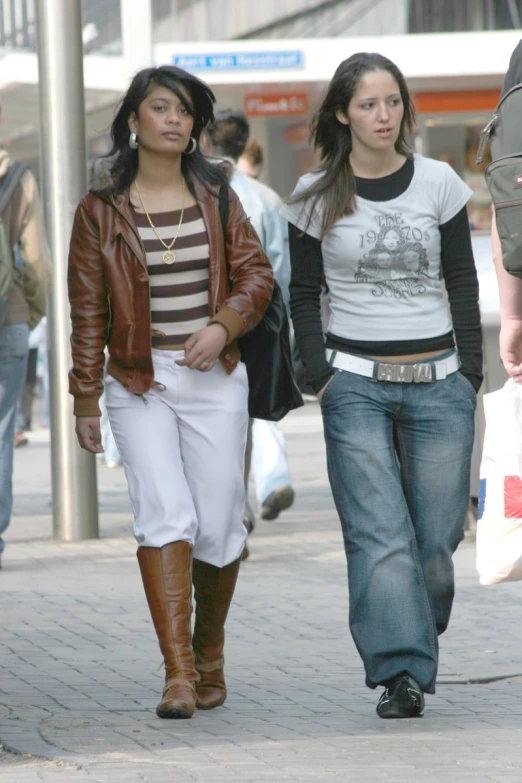 two young women walk down the street holding shopping bags