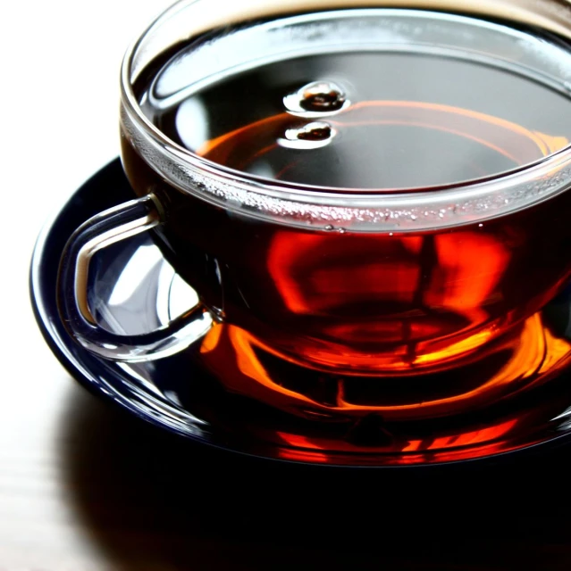 a glass of tea on a saucer with a spoon