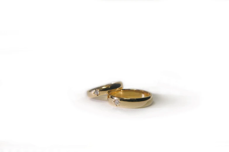 two gold colored wedding rings, one with a couple's diamond