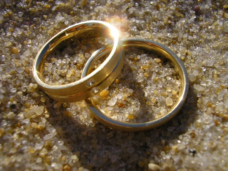 two gold colored wedding rings in some gravel