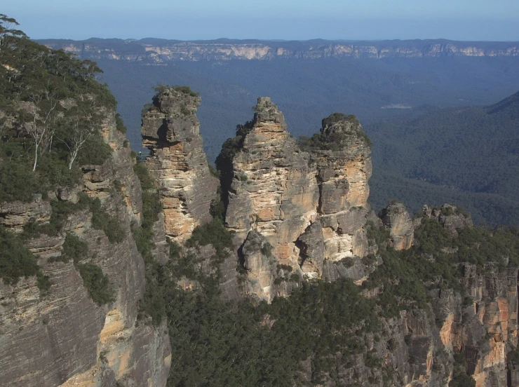 three large rocks sitting near a forest in a mountain