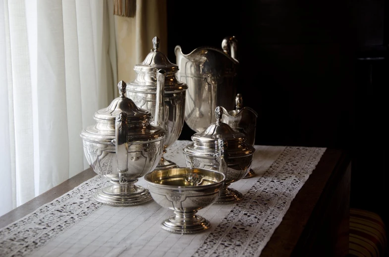 a table is decorated with silver dishes