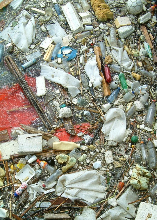 many plastic objects litter in a pile, including a baseball bat and broken bottle caps