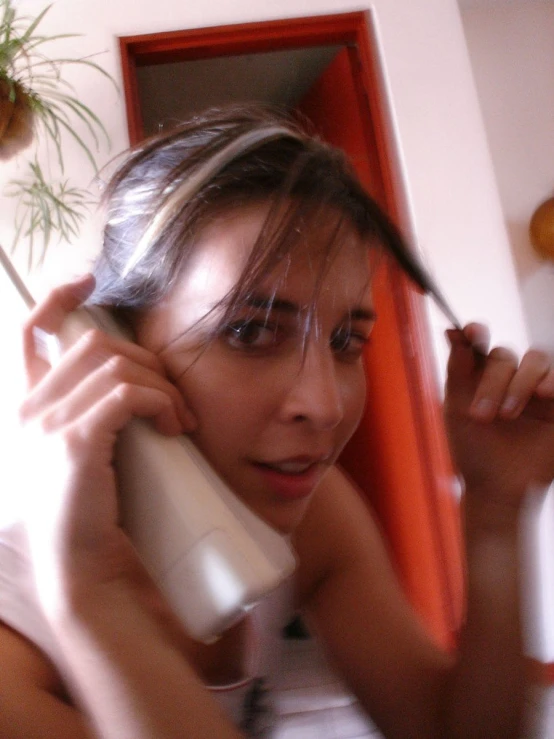 a woman brushes her hair and talks on the phone