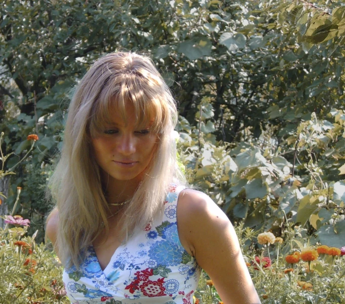 a pretty blonde woman standing in a lush green field