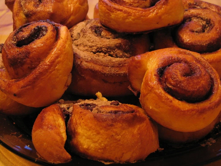 a brown plate of cinnamon rolls on top of a wooden table