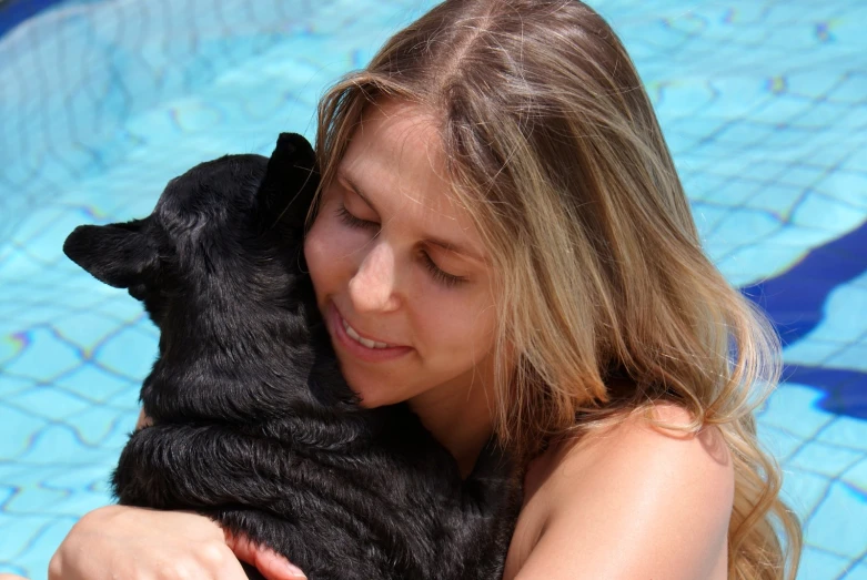 the woman is holding a dog outside near a pool