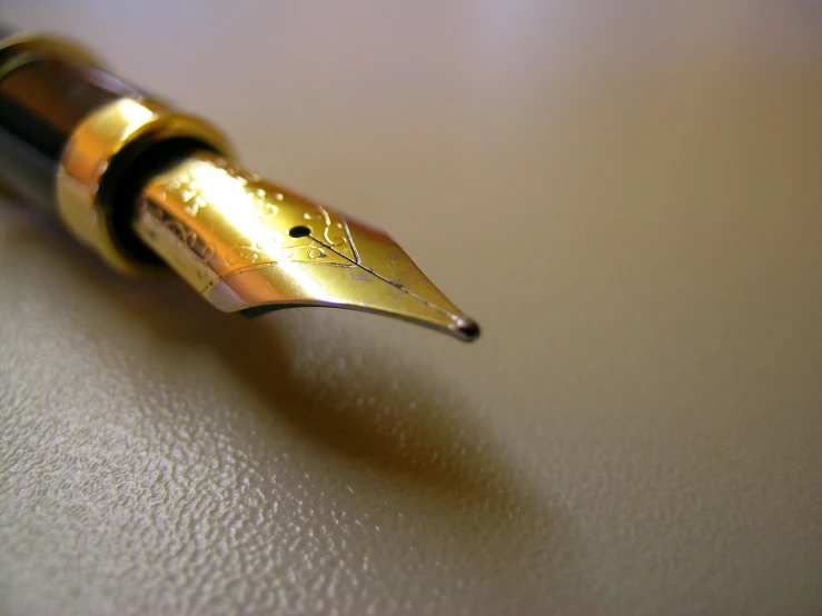 a fountain pen with a gold cap sitting on a table