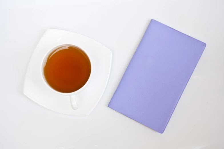 a cup of tea and a notebook next to each other