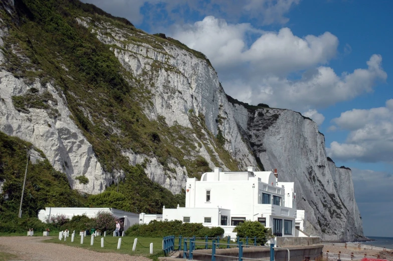 a white house is by the water by some cliffs