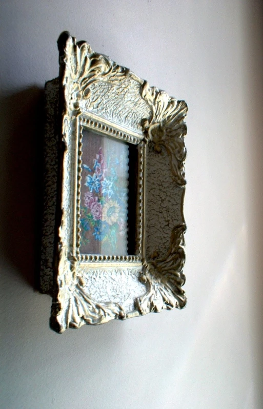 an ornate framed flower picture hanging on a wall