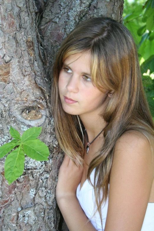 a woman that is leaning up against a tree