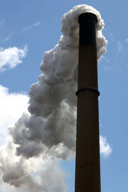 large factory emits white smoke and steam as it is billowing out into the sky