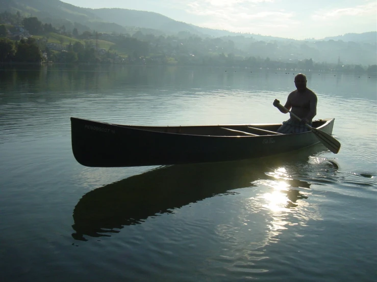 a man that is sitting on the back of a canoe