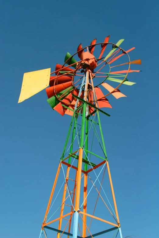 a green, yellow and red windmill against a blue sky