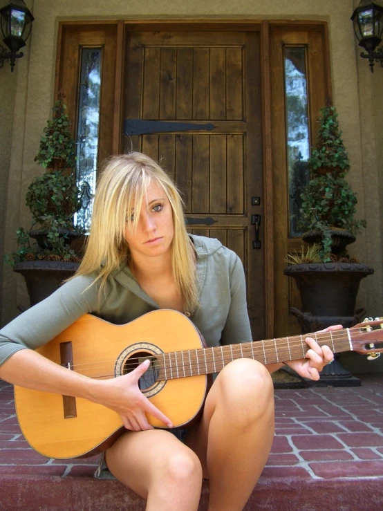 there is a woman sitting and playing an acoustic guitar