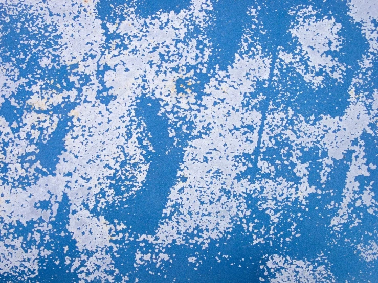 white paint peeling down from the surface of a blue and white wall