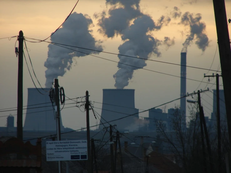 the smoke stacks of a power plant emitting black smoke