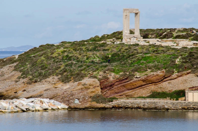 an outdoor structure on a hill beside water