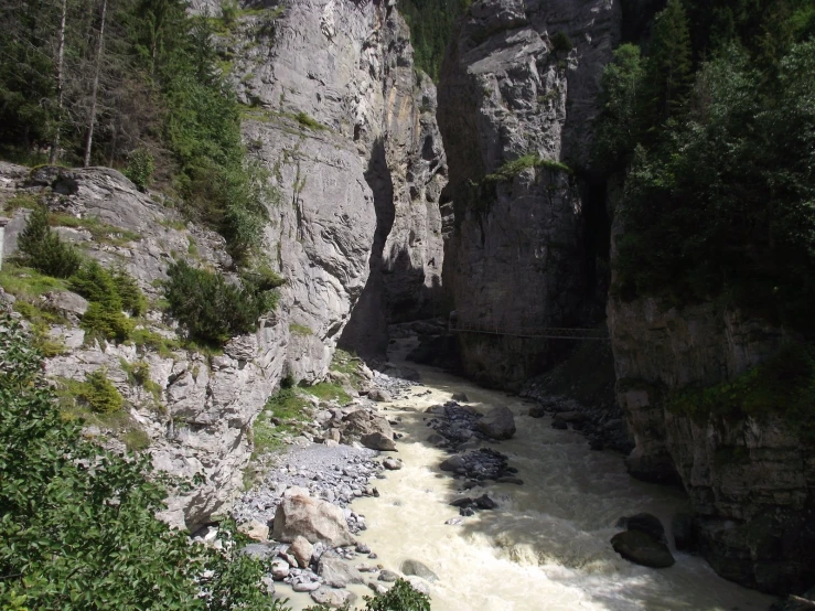 a scenic, rocky river next to tall cliff