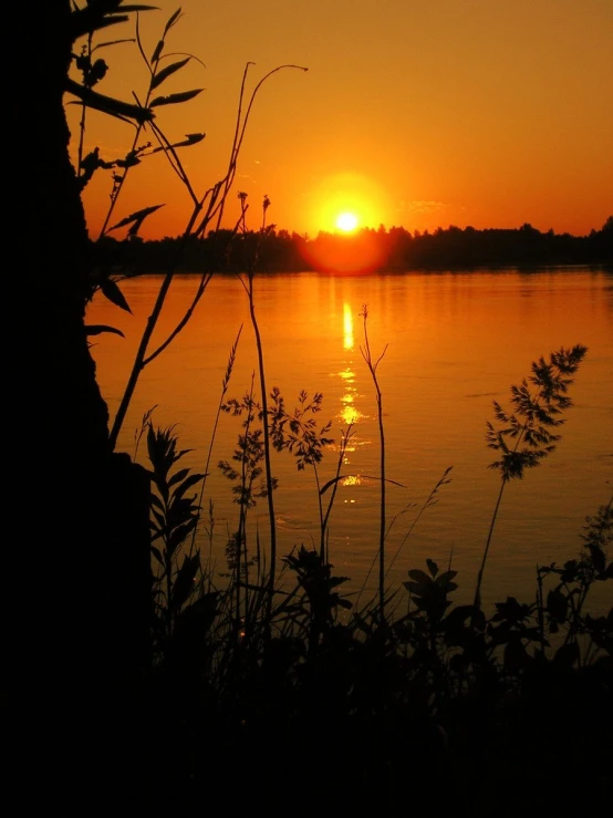 a sunset with the sun setting over a body of water