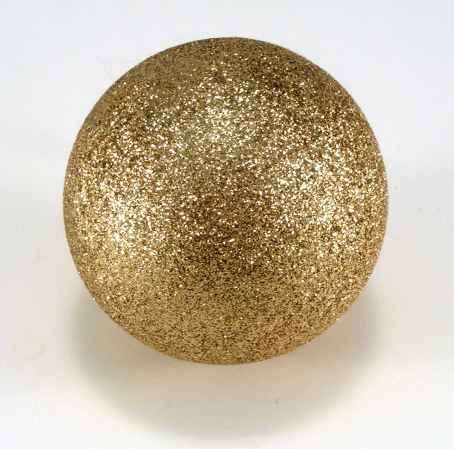 an empty gold glitter ball on a white surface