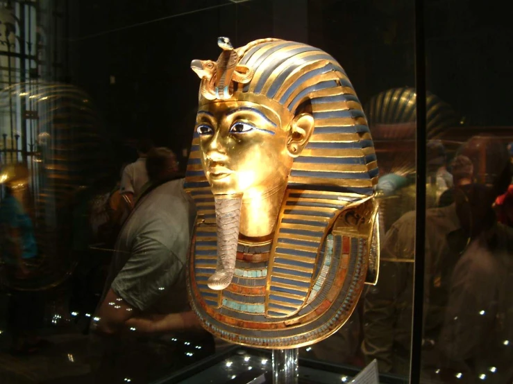 a golden sculpture of a head inside of a glass case