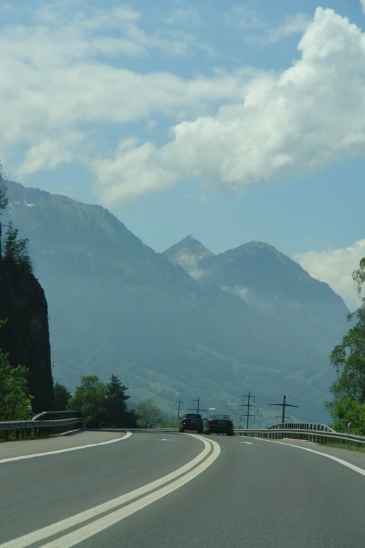 a car driving down the road toward the mountains