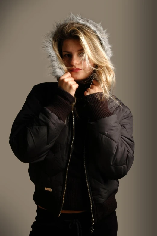 an attractive young woman in black jacket holding onto the hood
