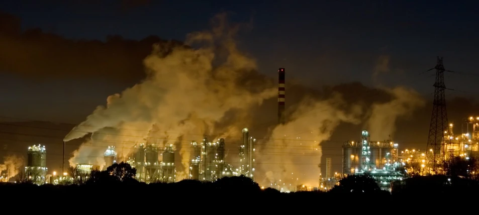 smoke billowing from an industrial power plant at night